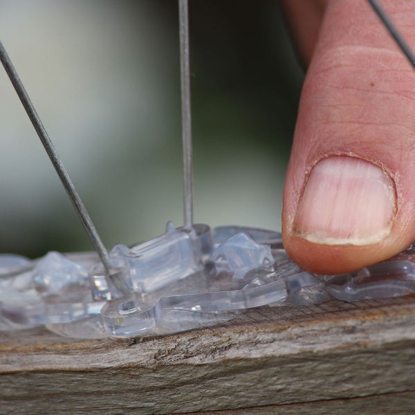 Defender® Narrow Stainless Steel Bird Spikes being installed using Defender Silicone with glue oozing through base